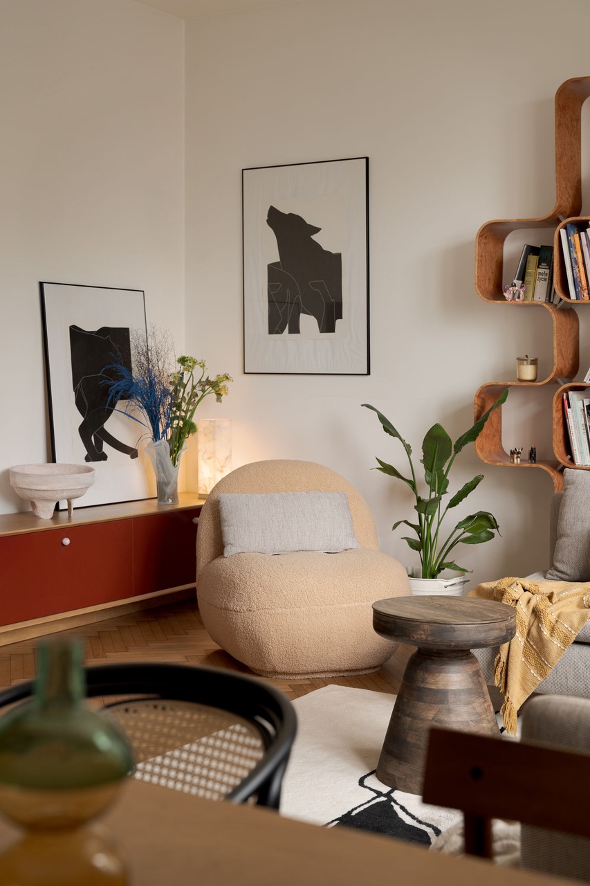 Przytulny salon z designerskimi plakatami i drewnianymi półkami.