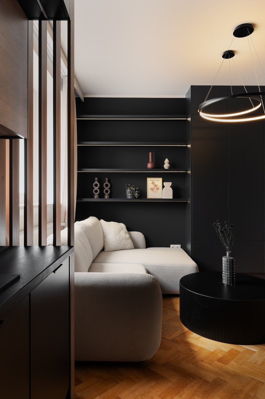 Elegancki salon z czarnymi półkami i nowoczesnym oświetleniem.