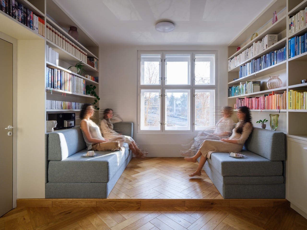 Salon z elegancką sofą i regałami pełnymi książek.