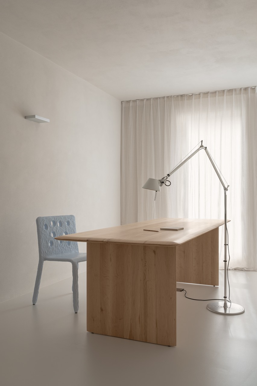 Minimalistyczne biuro z drewnianym biurkiem i nowoczesną lampą.