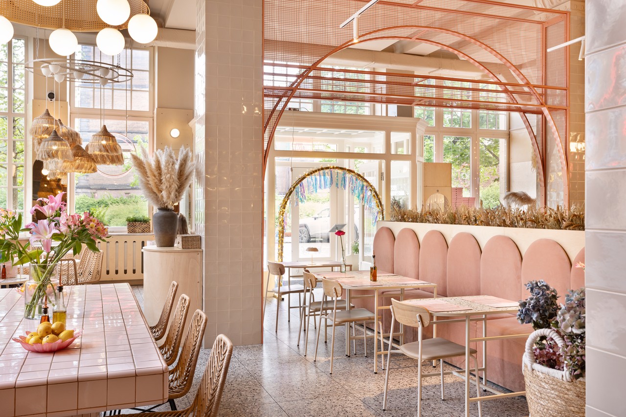 Restauracja w pastelowych barwach z ozdobnymi lampami i kwiatami.