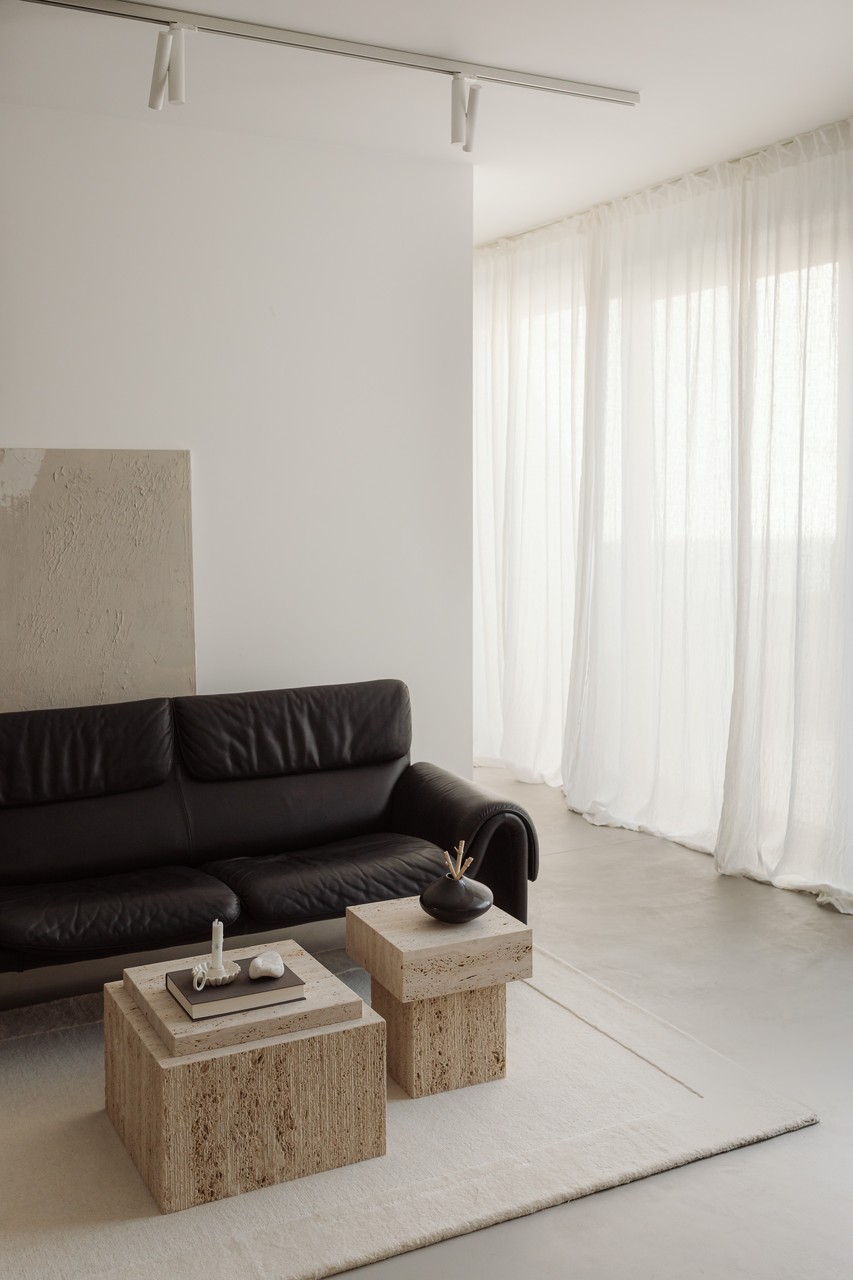 Nowoczesny salon z czarną sofą i stolikami z naturalnego kamienia.