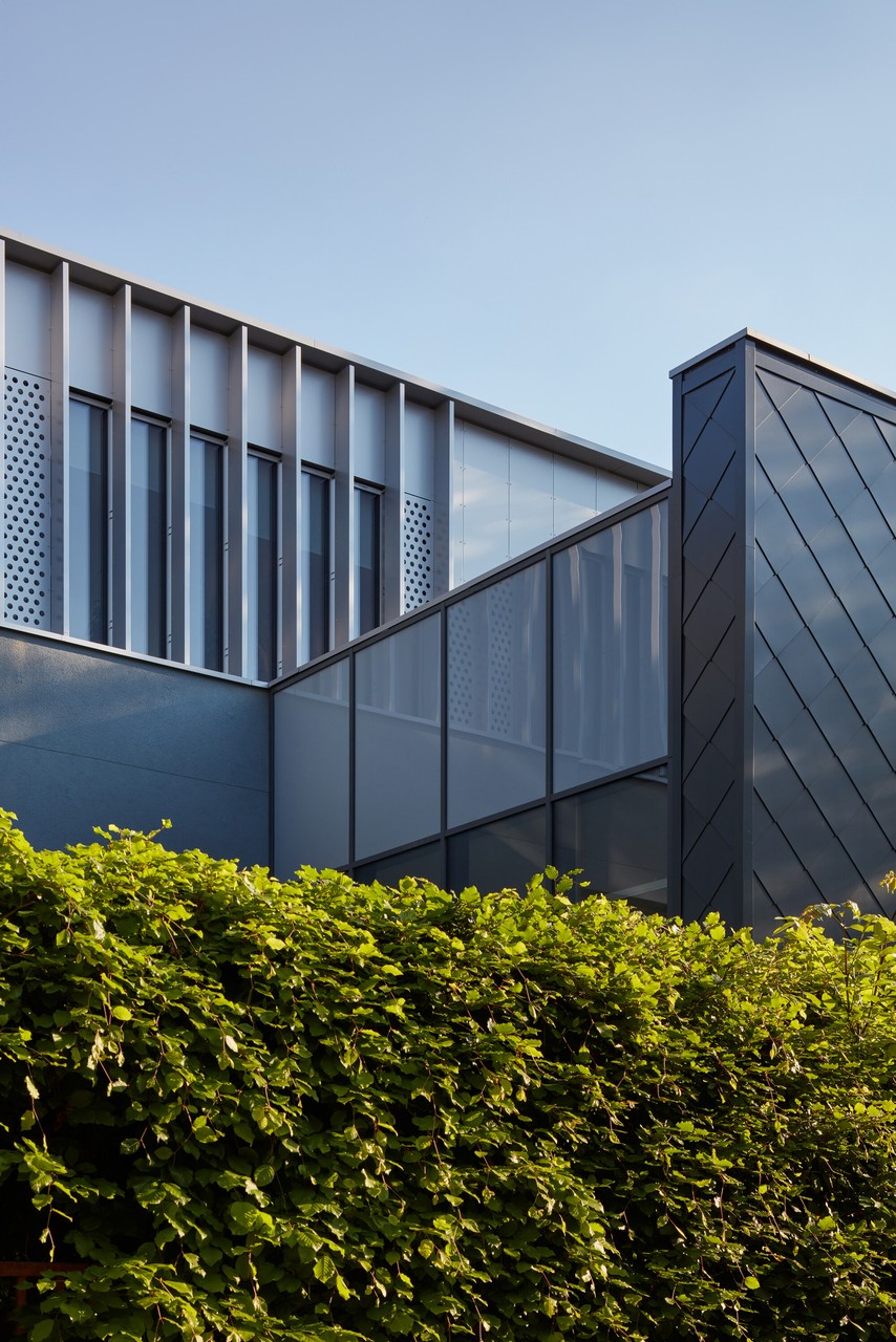 Nowoczesna architektura z przeszklonymi panelami i zielenią.