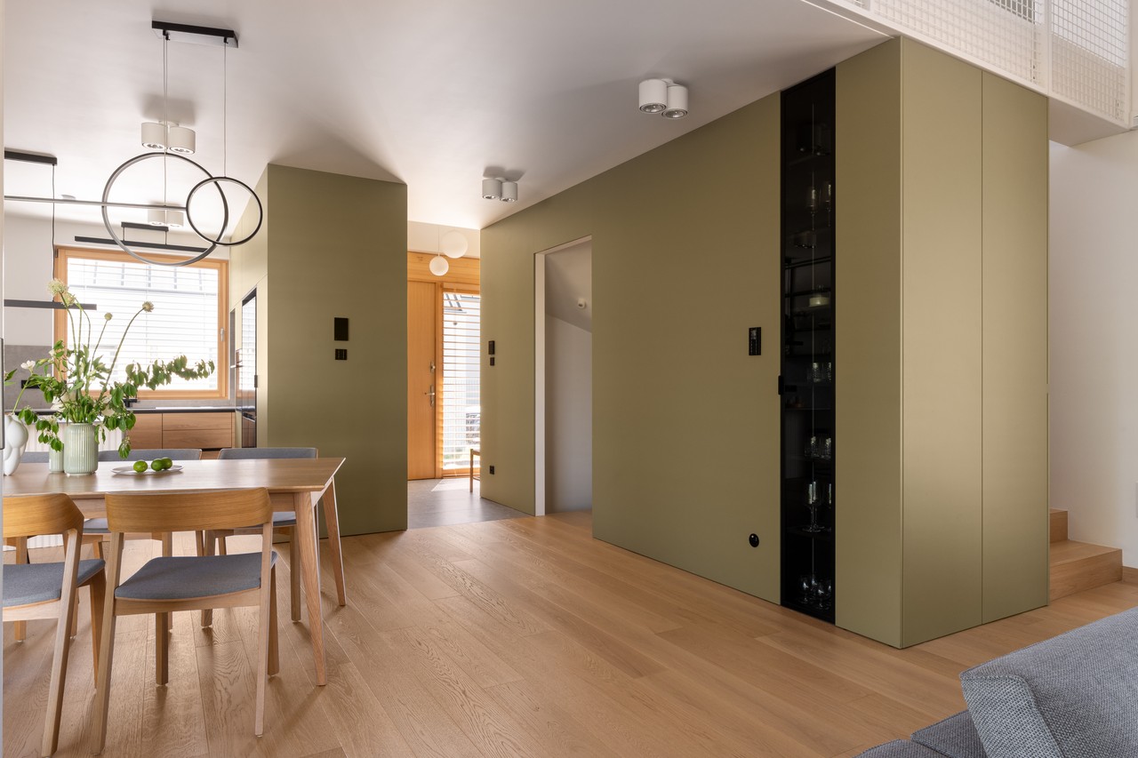Nowoczesna jadalnia z drewnianą podłogą i designerskimi lampami.