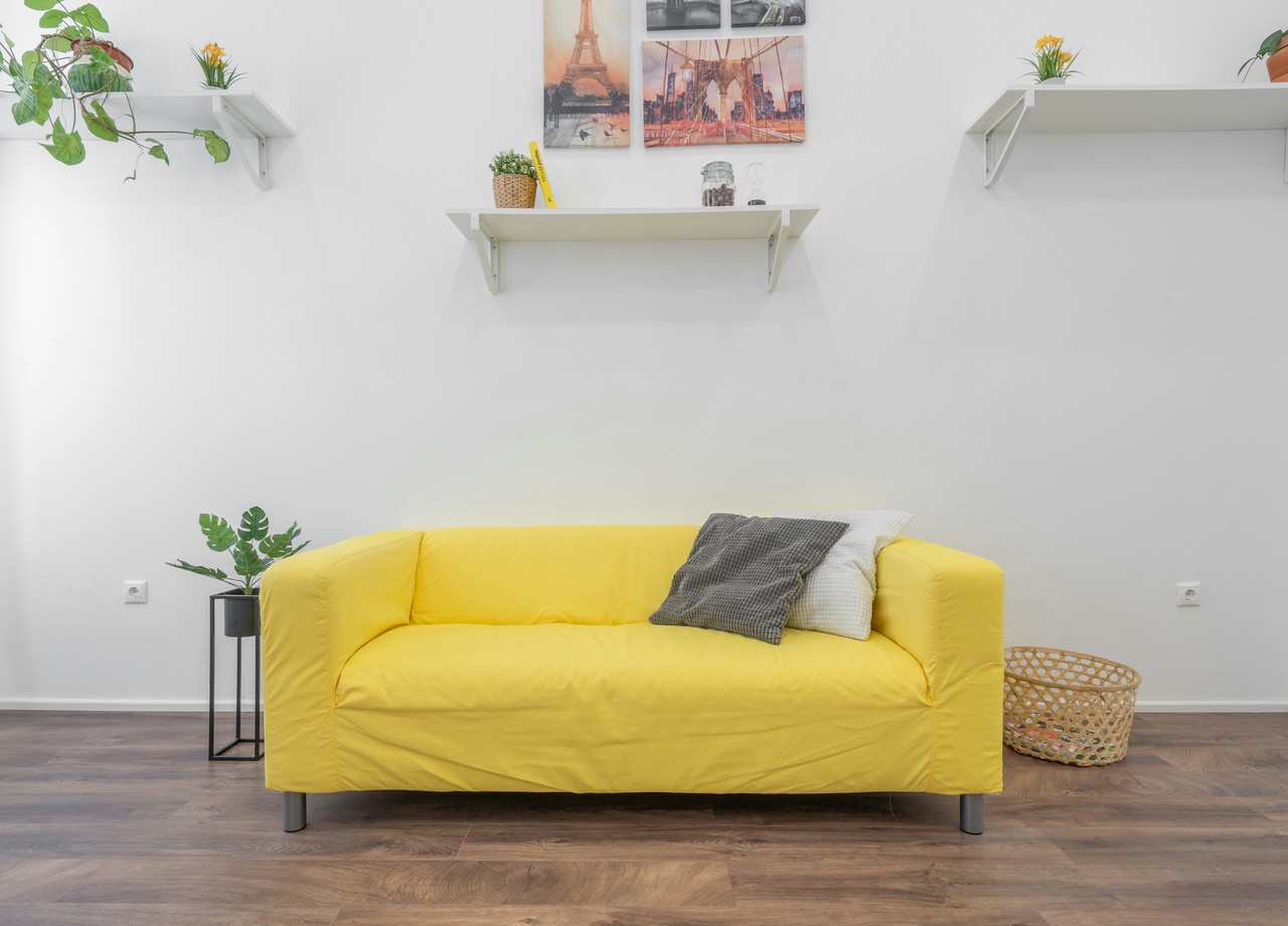 Nowoczesny salon z żółtą sofą i dekoracyjnymi półkami.
