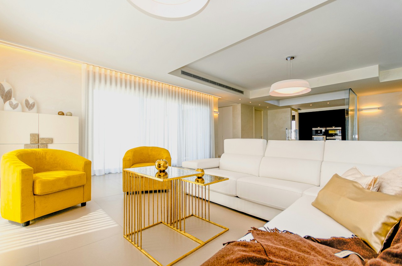 Nowoczesny salon z białą sofą i żółtymi fotelami.