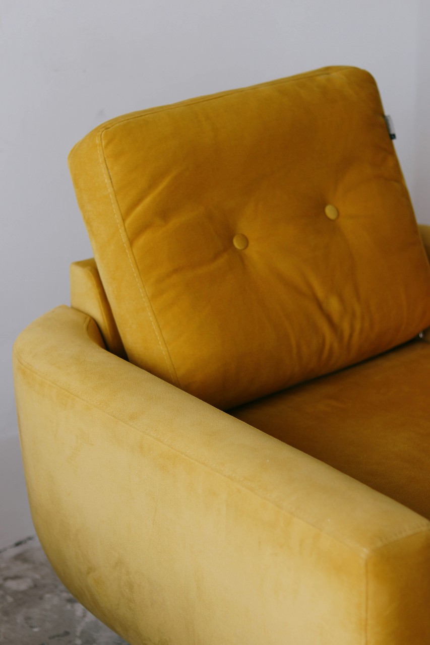 Stylowy musztardowy fotel z eleganckim pikowaniem.