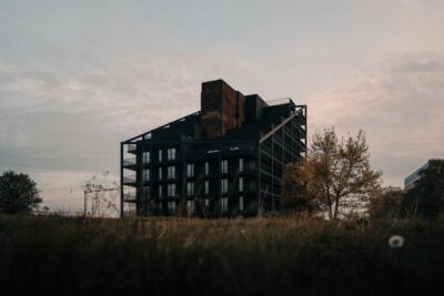 Ciemny budynek z nowoczesną architekturą w otoczeniu drzew.