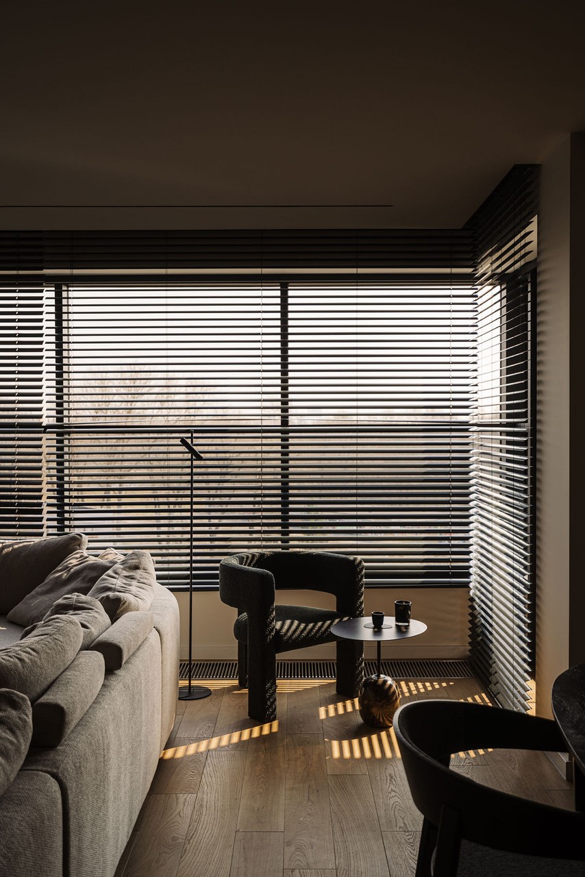 Elegancki salon z nowoczesnymi żaluzjami i designerskim fotelem.