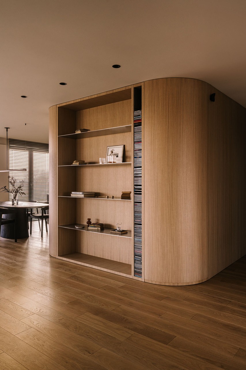 Drewniana biblioteczka w nowoczesnym wnętrzu z eleganckimi akcentami.