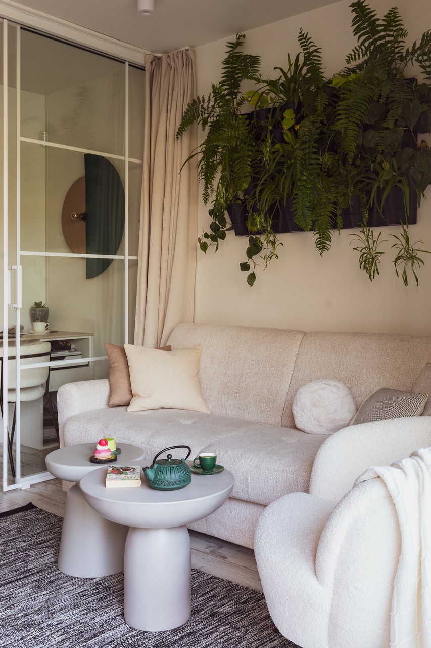 Przytulny salon z sofą, zielenią i designerskimi stolikami.