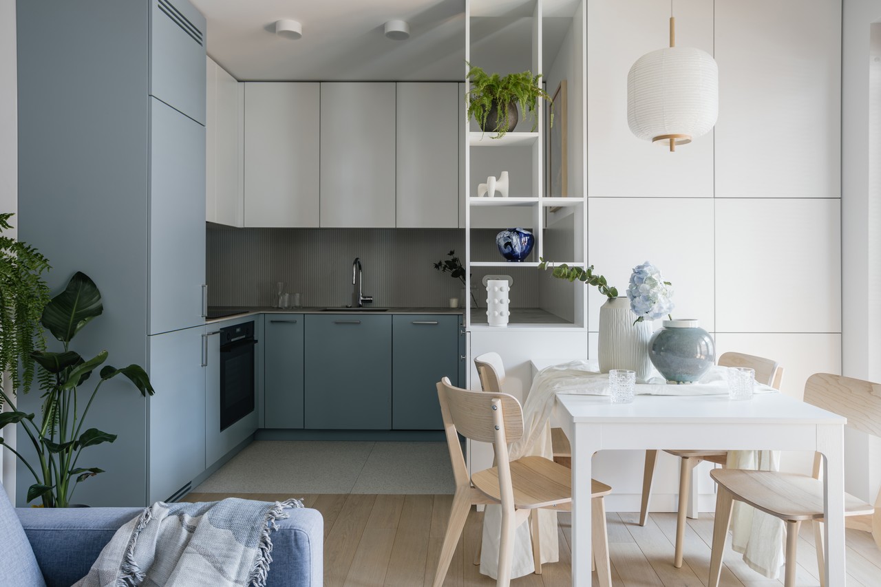 Salon z jasną kuchnią i minimalistycznym stołem, elegancja stylu skandynawskiego.