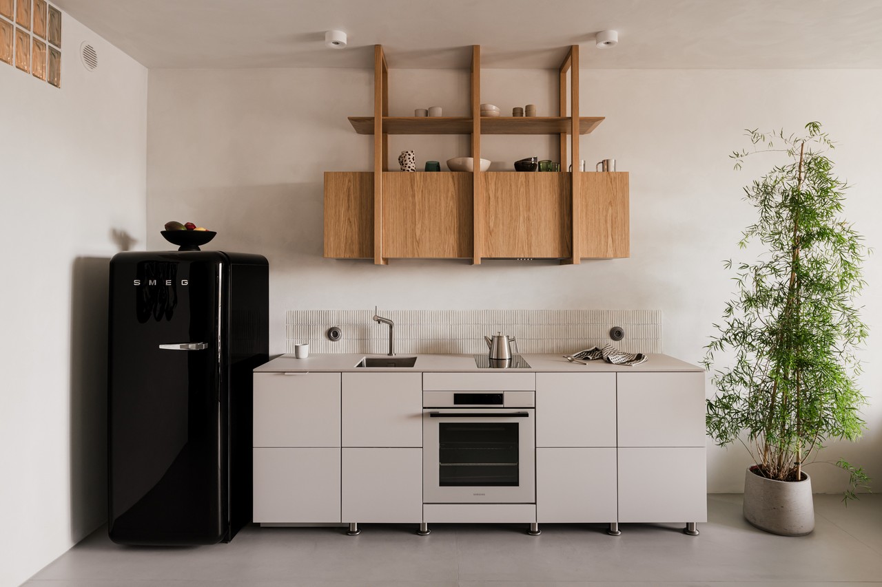 Kuchnia minimalistyczna z retro lodówką i drewnianymi półkami.