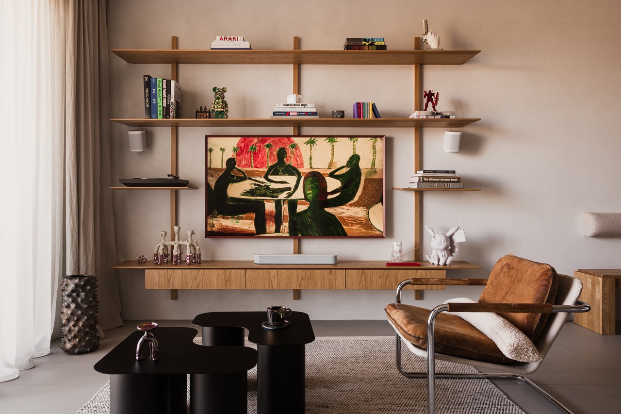 Nowoczesny salon z obrazem, półkami i designerskim fotelem.