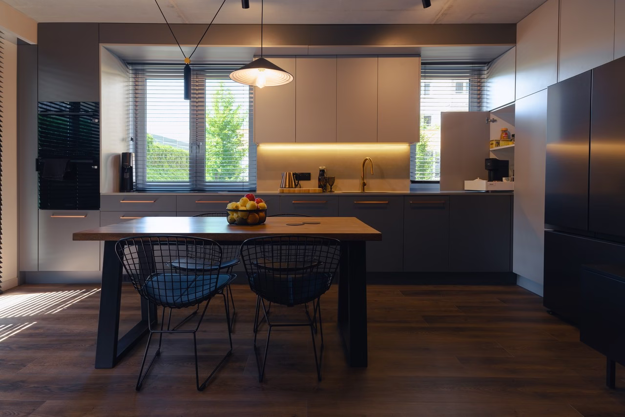 Nowoczesna kuchnia z drewnianym stołem i designerską lampą.