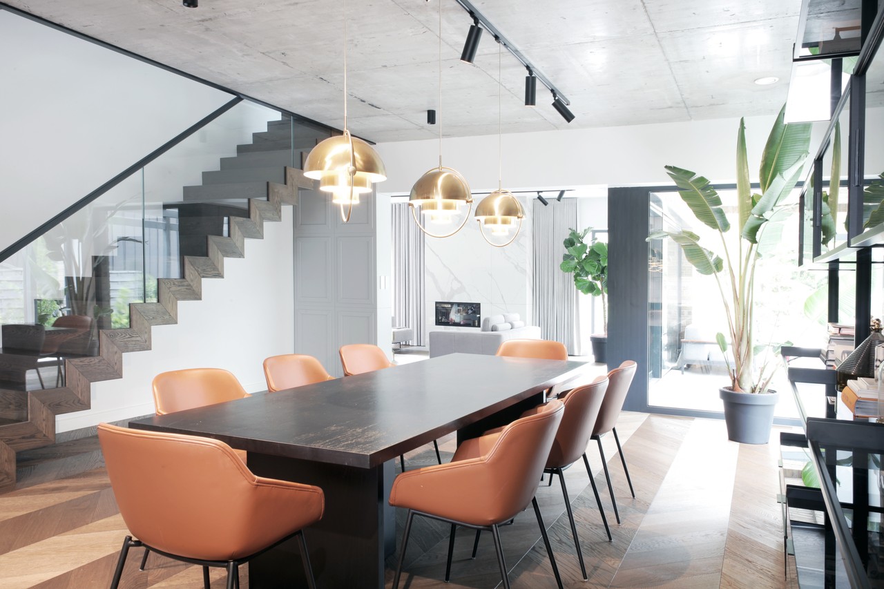 Nowoczesna jadalnia z designerskimi krzesłami i złotymi lampami.