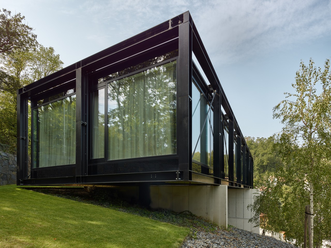 Nowoczesna architektura z przeszkloną elewacją w otoczeniu natury.