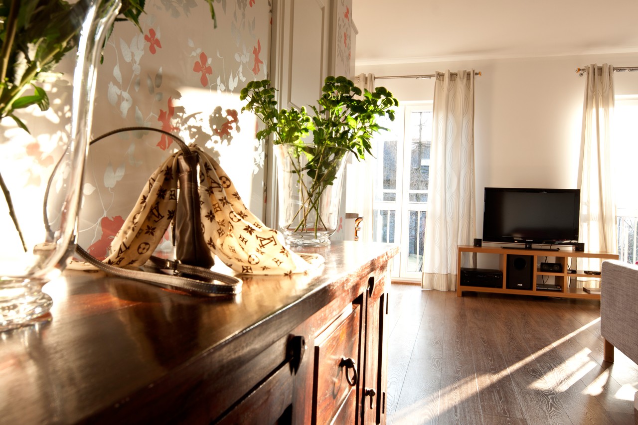 Przytulny salon z eleganckimi dodatkami i dużymi oknami.