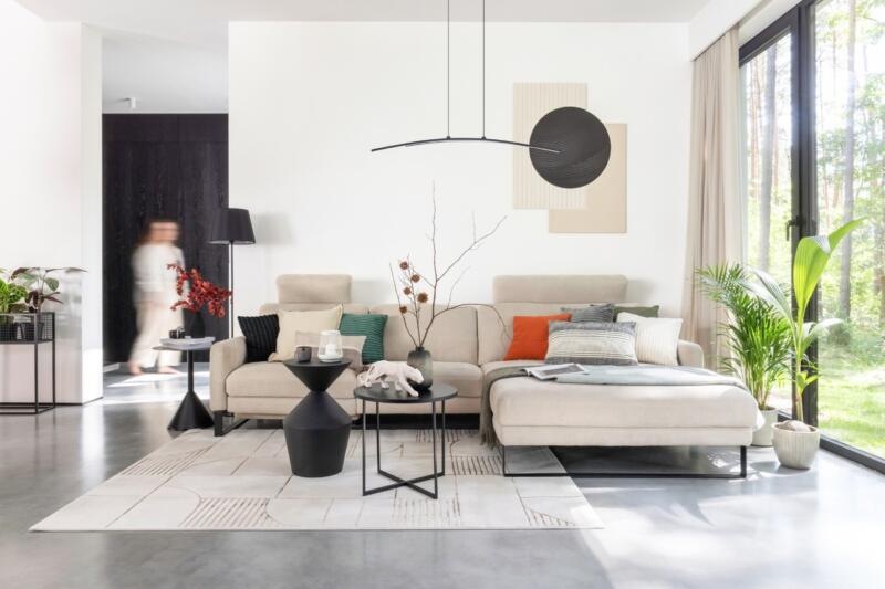 Modern living room with beige sofa, floral accents and bright interior.