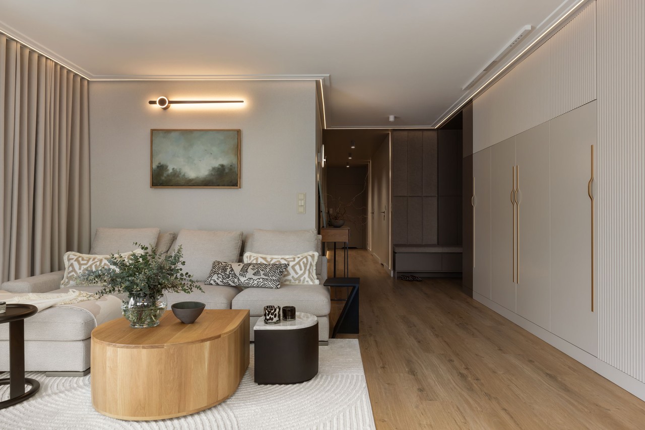 Nowoczesny salon z beżową sofą i drewnianym stolikiem.