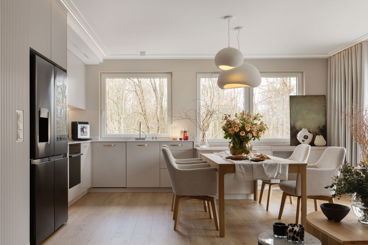 Jasna kuchnia z eleganckim stołem i designerskimi lampami.