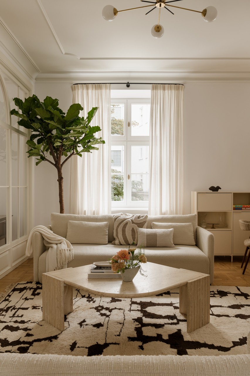 Elegancki salon z beżową sofą i geometrycznym stolikiem.