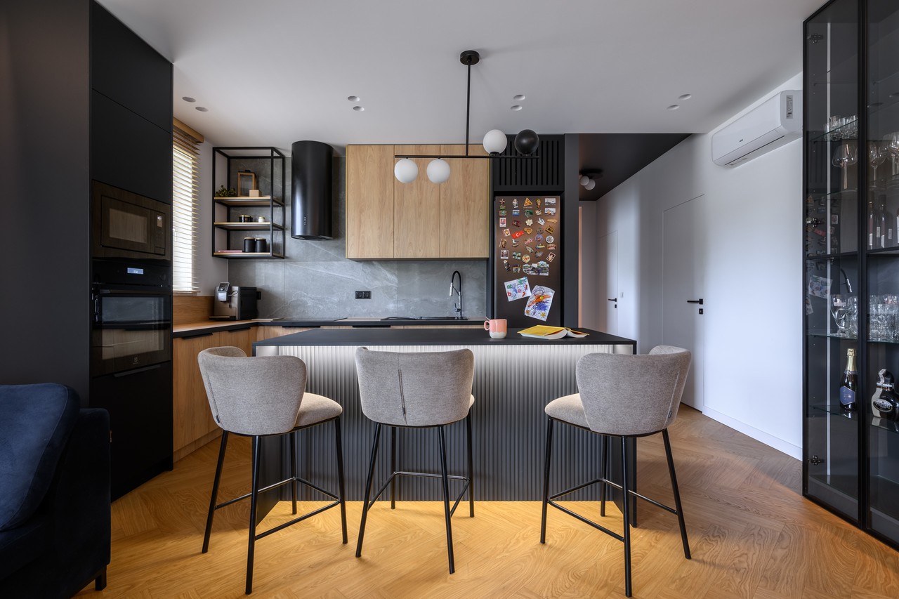 A modern kitchen with wood, an island and designer chairs.