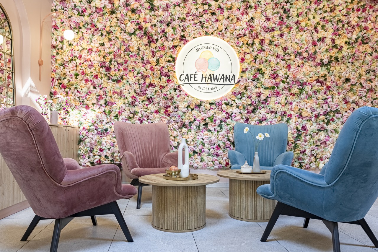 Kwiatowa ściana z designerskimi fotelami w pastelowych kolorach.