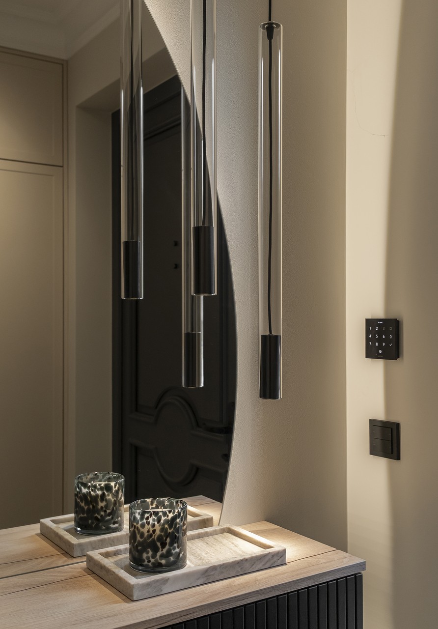 Elegancka lampa wisząca i designerskie akcesoria na drewnianym blacie.