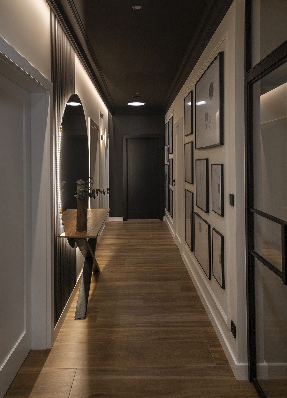 Elegancki korytarz z drewnianą podłogą i designerskim lustrem.