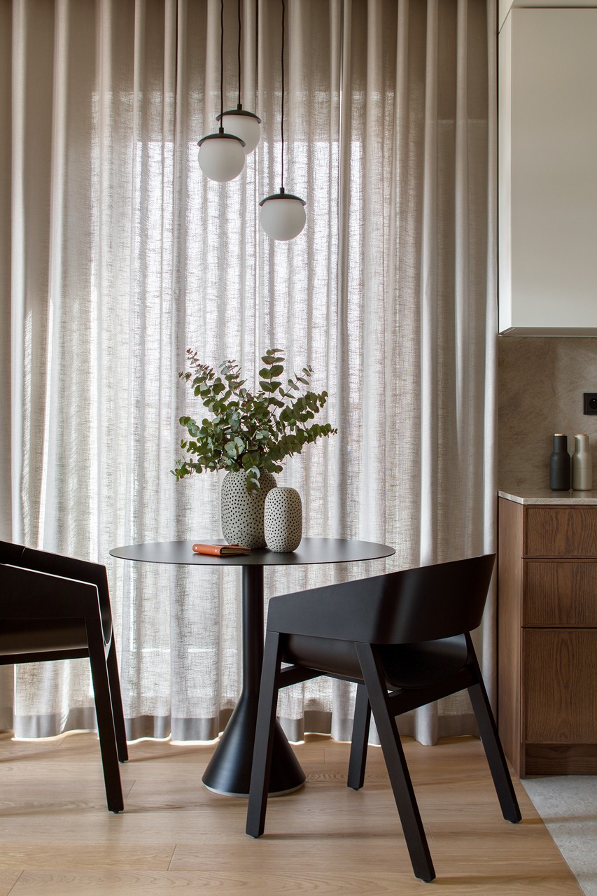 A modern dining room with a designer table and a plant in a vase.