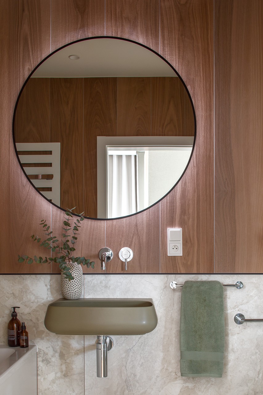 A modern bathroom with a round mirror and an elegant sink.