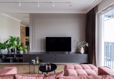 Modern living room with pink sofa and plants against a grey wall.
