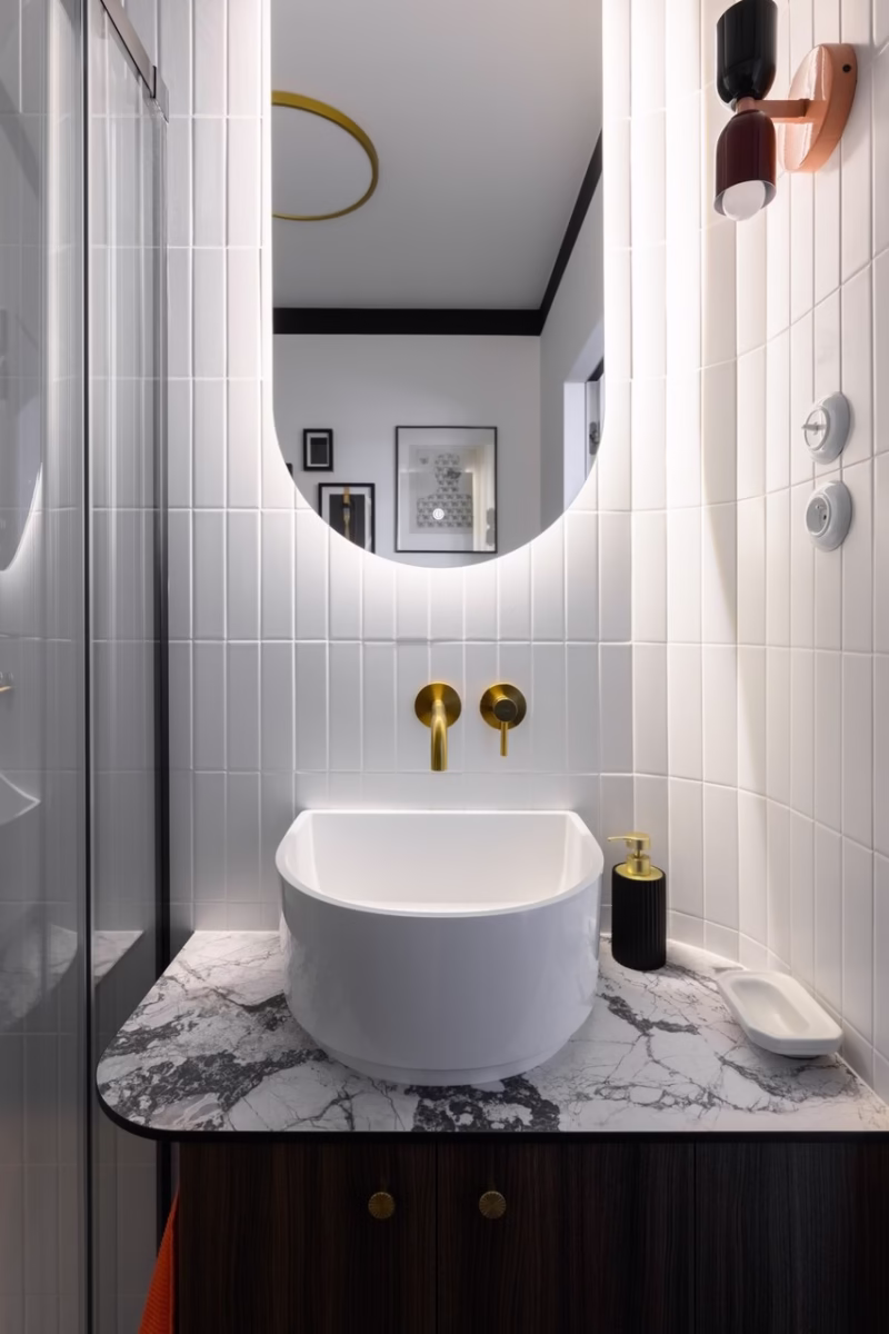 A washbasin in a stylish bathroom with marble top and gold fittings.