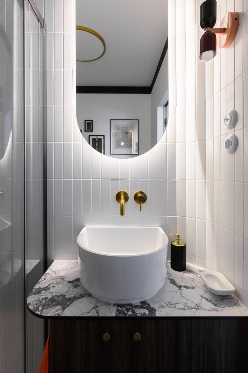 A washbasin in a stylish bathroom with marble top and gold fittings.