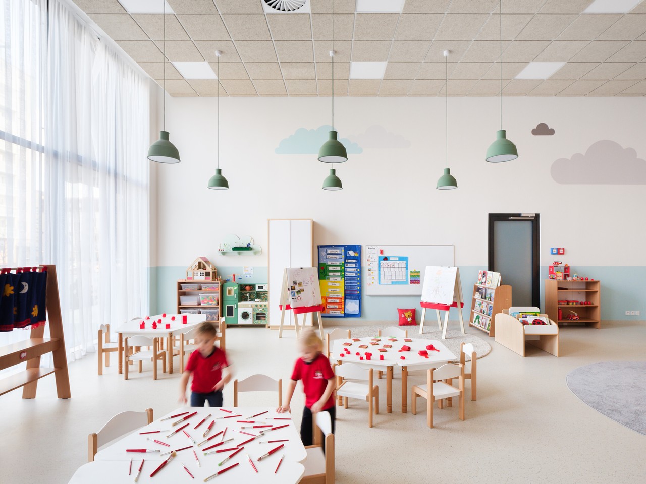 Przestronna sala przedszkolna z nowoczesnym wystrojem i jasnym światłem.