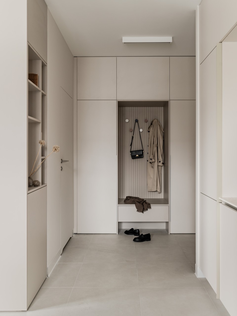 Przestronny minimalistyczny przedpokój z eleganckimi wieszakami.