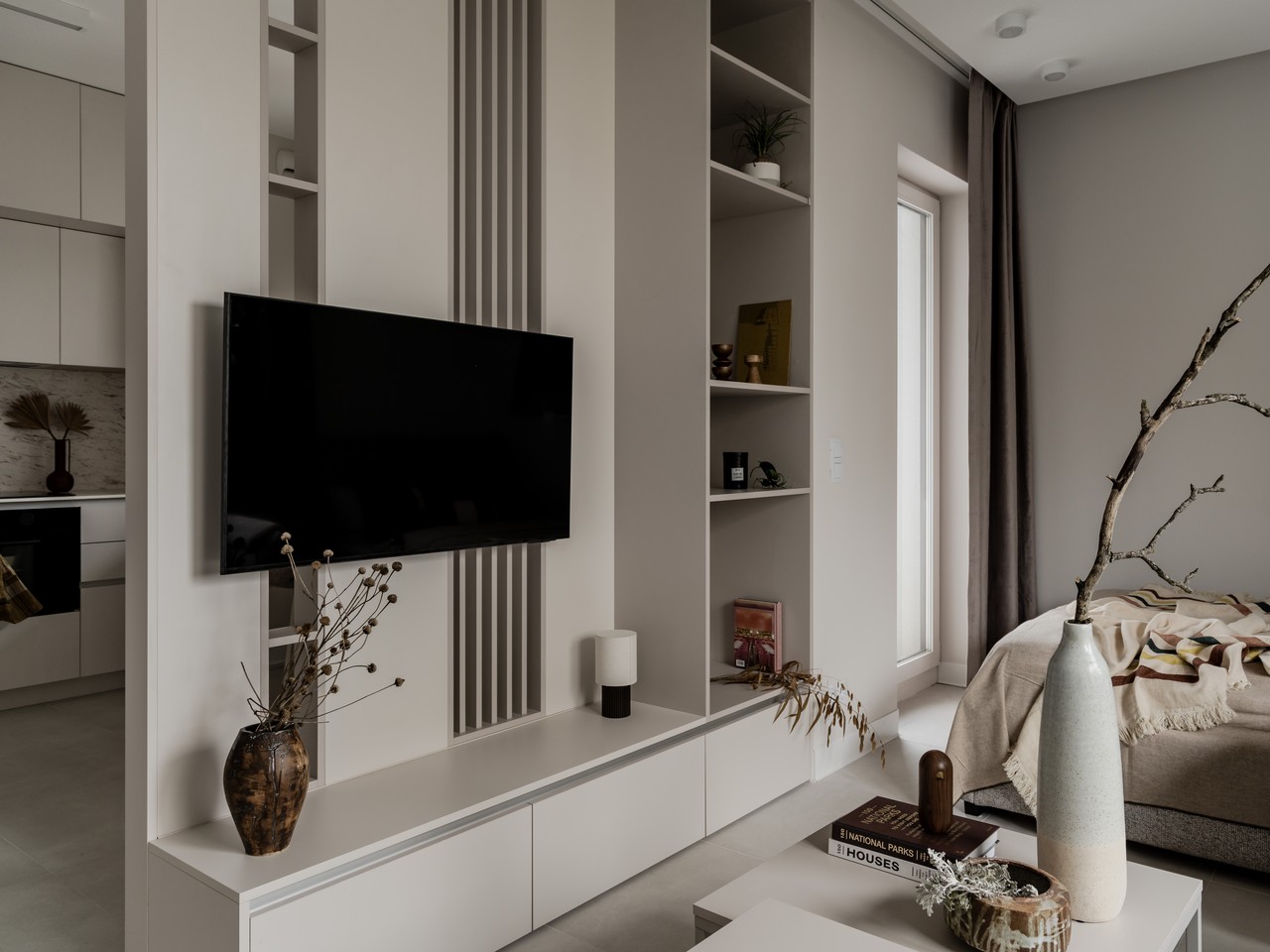 Minimalistyczny salon z nowoczesnym telewizorem i eleganckimi dodatkami.