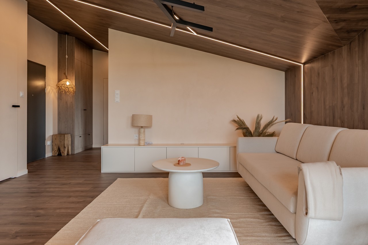 Nowoczesny salon z beżową sofą i drewnianymi akcentami.