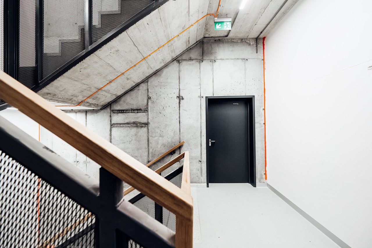 Minimalistyczne schody z surowym betonem i industrialnym detalem.