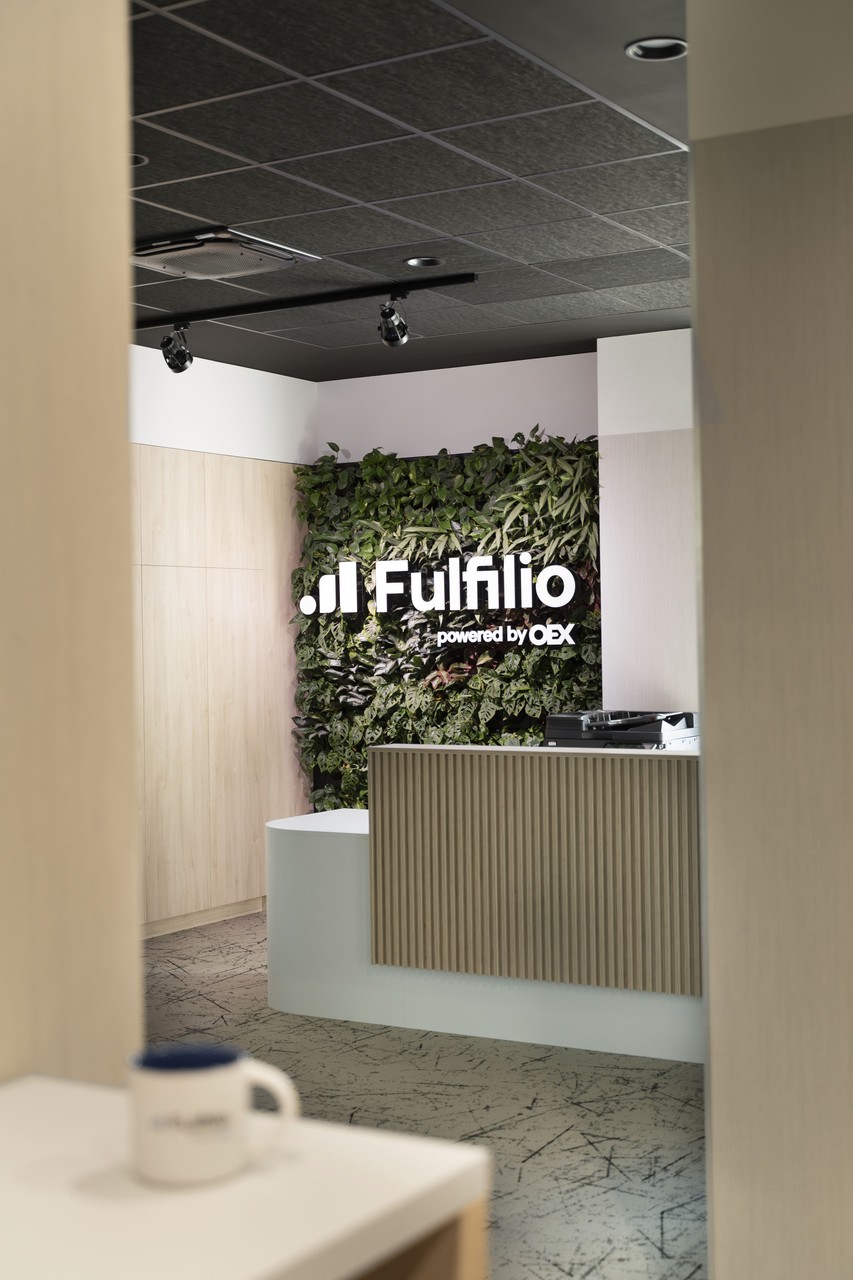 Biophilic design recepcji z zieloną ścianą i nowoczesnym logo.