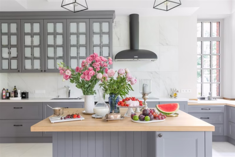 Modern kitchen with flowers and fruit on a wooden countertop.