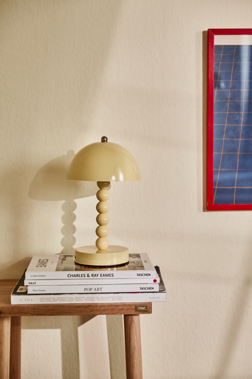 Lampa o nowoczesnym designie na stosie książek o architekturze.