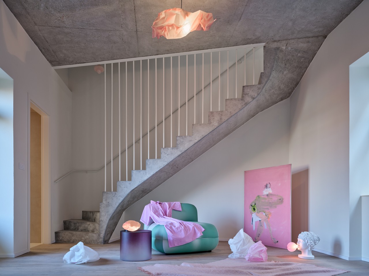 Nowoczesne wnętrze z betonowymi schodami i pastelowymi dodatkami.