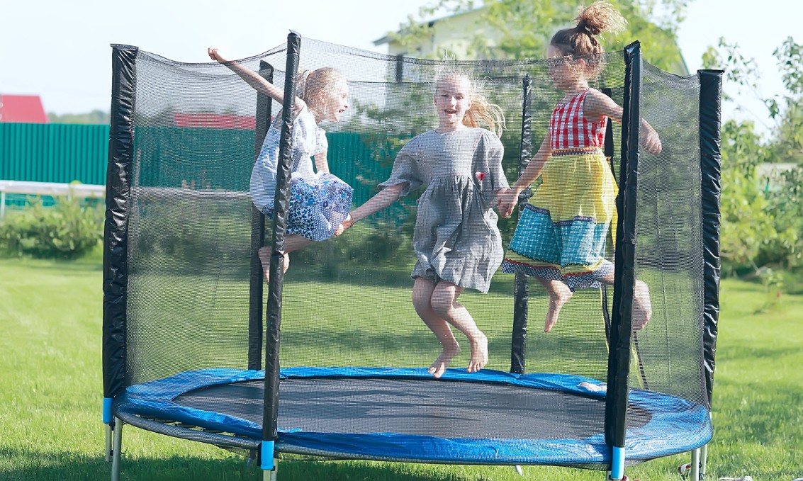 Dzieci bawiące się w ogrodzie na trampolinie. Świeżość i radość.