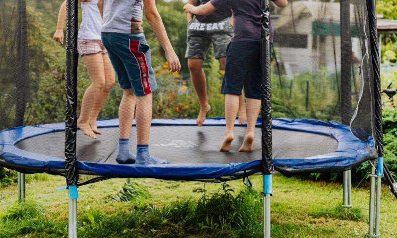 Dzieciństwo na trampolinie w przydomowym ogrodzie.