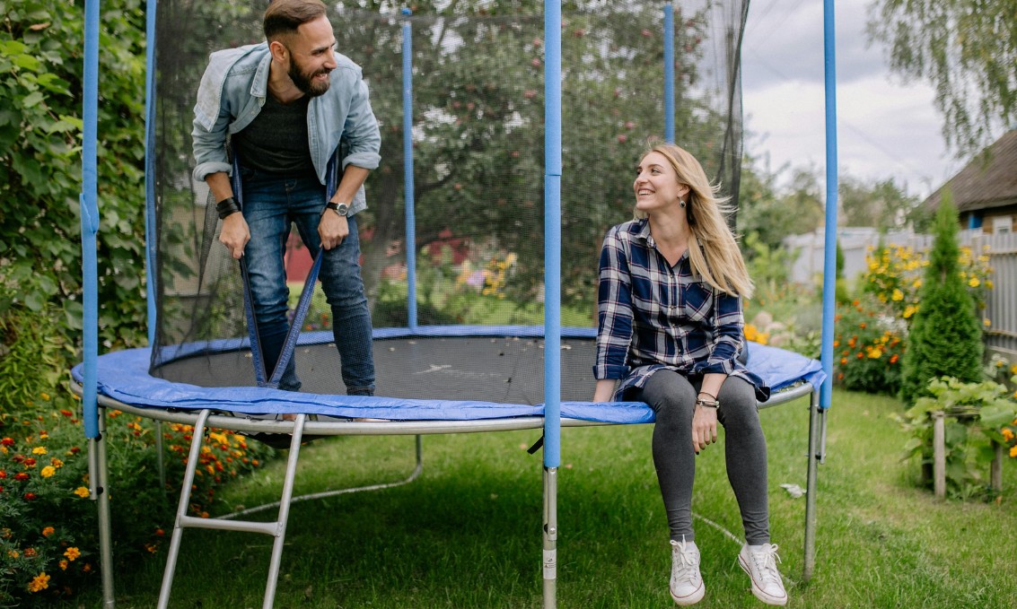 Ogród z trampoliną w letnim klimacie, zielona przestrzeń relaksu.