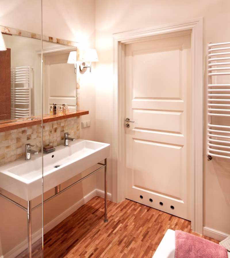 Elegancka łazienka z drewnianą podłogą i stylowym oświetleniem.