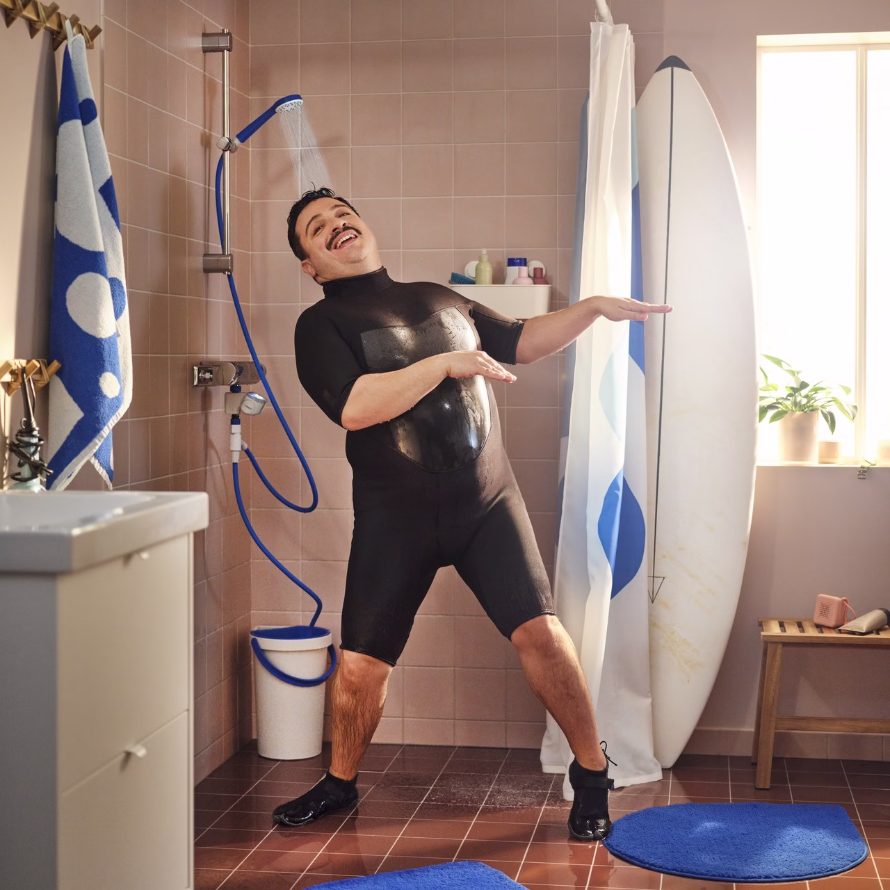 Mężczyzna pod prysznicem w nowoczesnej łazience z deską surfingową.