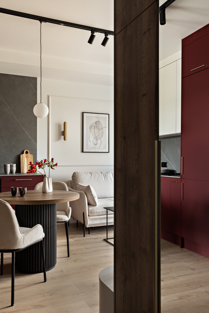 Nowoczesny salon z bordową kuchnią i eleganckimi meblami.